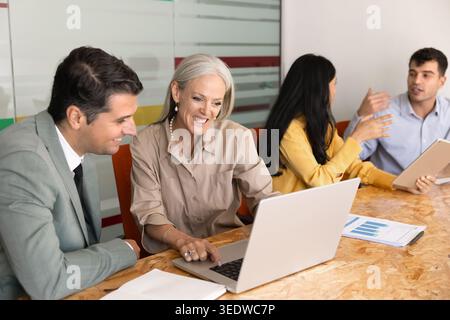 Corporate team members working together on project using laptop Stock Photo