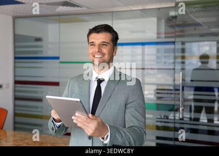 Caucasian businessman working on digital tablet in corporate office Stock Photo
