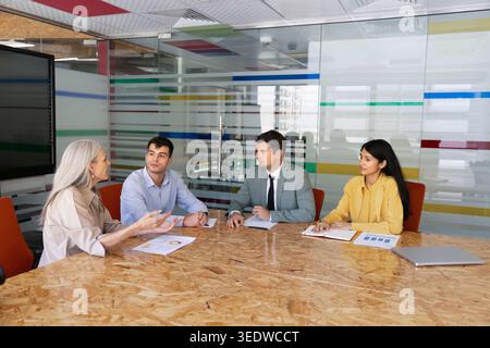 Diverse businesspeople sitting in conference room discussing financial reports data Stock Photo