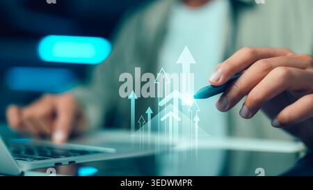 Businessman using stylus pen touching glowing rising arrows on virtual screen. Business growth, financial success, investment strategy and corporate d Stock Photo