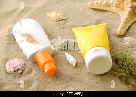 Two sunscreen containers on beach sand with seashells and starfish in bright summer sunlight, evoking vacation and sun protection. Stock Photo