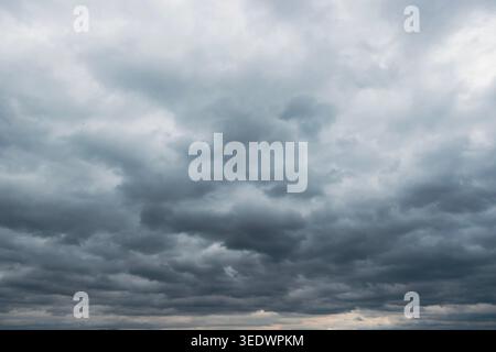 Dark storm clouds gathering across dramatic overcast sky before rain, moody weather background landscape Stock Photo