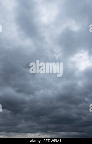 Dark storm clouds gathering across dramatic overcast sky before rain, moody weather background landscape Stock Photo