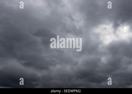 Dark storm clouds gathering across dramatic overcast sky before rain, moody weather background landscape Stock Photo