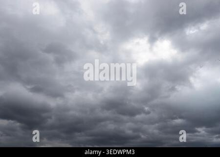 Dark storm clouds gathering across dramatic overcast sky before rain, moody weather background landscape Stock Photo