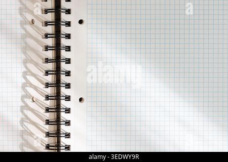 Blank white squared notebook page with metallic spiral binding background with lights and shadows. template mockup Stock Photo