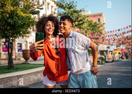 Young students relaxing and enjoying a city break, using their mobile phone to capture a moment Stock Photo