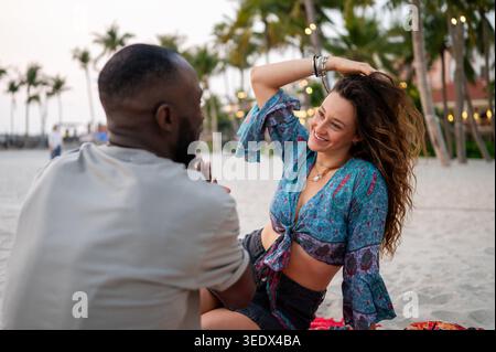 Happy couple enjoys the pure joy of life while relaxing on a tropical beach at dusk Stock Photo