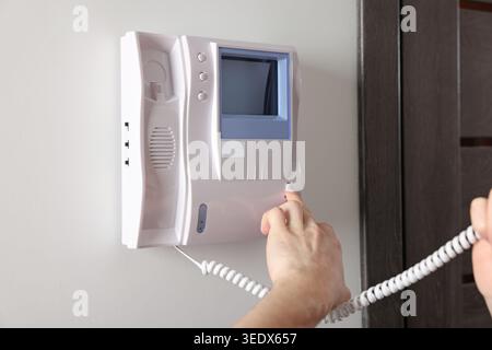 Man pressing button on intercom panel indoors, closeup Stock Photo