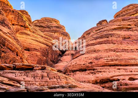 Dramatic red sandstone cliffs and unique rock formations at Jabal Ithlib in the ancient Nabataean site of Hegra, Al Ula, Saudi Arabia. Stock Photo