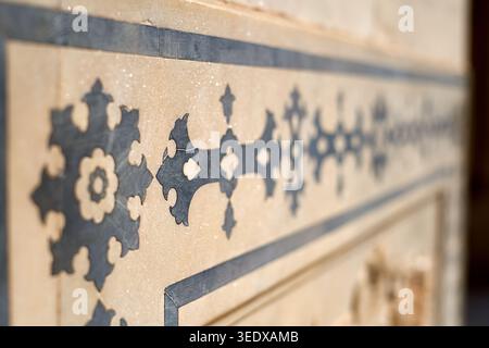 Close-up detail of intricate pietra dura stone inlay work featuring dark colored semi-precious stones or marble set into a light cream marble Stock Photo