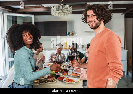 Diverse friends making a toast with wine glasses during a dinner party Stock Photo
