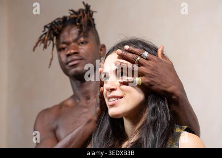Man covering woman's eyes, illustrating connection, diversity, and trust in a relationship Stock Photo