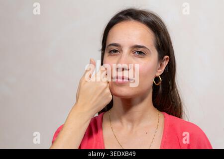 Woman forming a sign language word for communication on her cheek Stock Photo