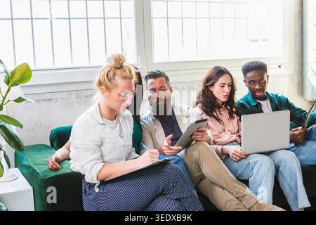 Diverse group of young entrepreneurs working on a project in a modern office Stock Photo