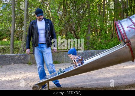 Father with toddler son on play ground having fun Stock Photo