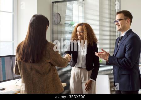 Business handshake in office meeting as colleague applauds, celebrating success Stock Photo
