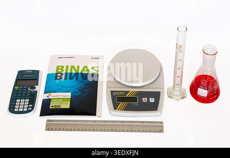 Set of science education materials: calculator, Binas, scale, measuring cylinder, ruler, and an Erlenmeyer flask with liquid. Stock Photo