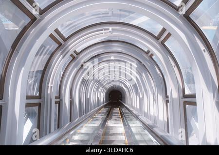 Osaka, Japan: Futuristic see-through glass escalator tunnel at Umeda Sky Building with glowing white circular structural rings. Travel background. Stock Photo