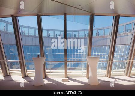 Osaka, Japan: Interior of sky high cafe at Umeda Sky Building with white bar tables and panoramic city views through curved glass windows. Stock Photo
