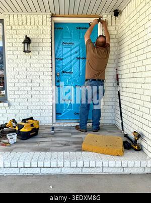 Caucasian man in his 40s installs a new colorful turquoise front door on a residential home in Wichita, Kansas, USA Stock Photo