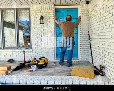 A workman fits a new front door onto a residential home in Wichita, Kansas, USA. Stock Photo