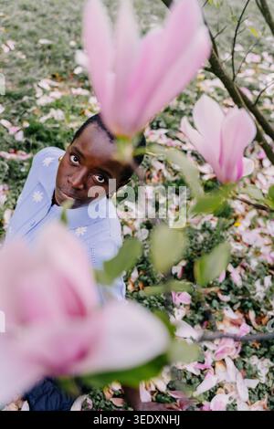 Intense African Female Portrait Looking Directly at Camera Through Pink Magnolia Flowers Stock Photo