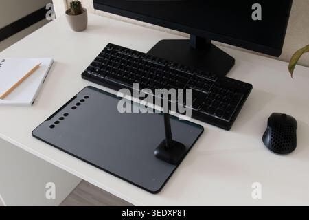 Top view of clean home office desk with graphic drawing tablet, stylus, computer monitor, keyboard, mouse, notebook and plants, concept of digital art Stock Photo