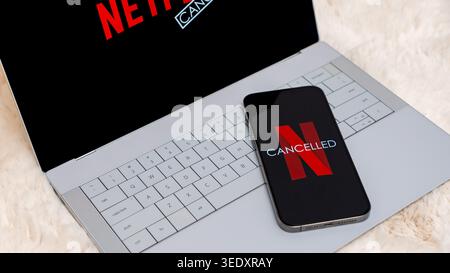 Laptop and smartphone displaying Netflix logo with Cancelled text, symbolizing surprise at subscription cancellation, featuring modern technology and Stock Photo