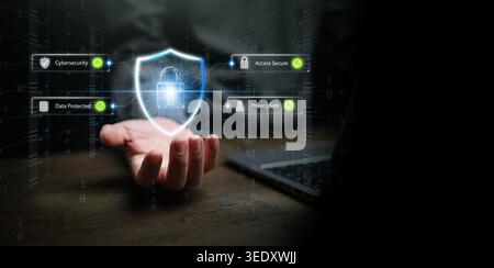 Hand next to laptop holding cybersecurity shield with digital lock and secure access icons. Data protected, privacy safe, cyber defense, network secur Stock Photo