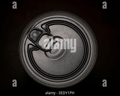 Top down macro view of a circular metal tin can lid with an integrated ring pull tab showing concentric textures and metallic highlights Stock Photo