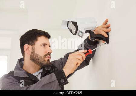 CCTV indoor wall setting, installing security camera, man holding screwdriver, fastening mount wall Stock Photo