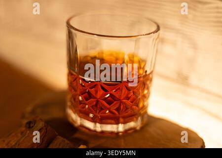 Crystal glass filled with amber whiskey, gently illuminated by warm light, highlighting rich tones, delicate reflections and the quiet elegance of a r Stock Photo
