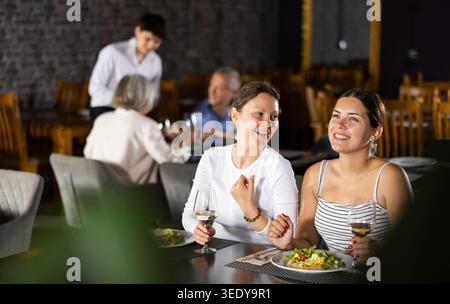 Young and adult women having dinner in restaurant Stock Photo
