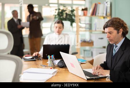 European man working on laptop with room in office Stock Photo