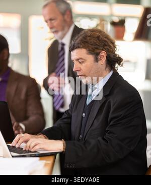 European man working on laptop with room in office Stock Photo