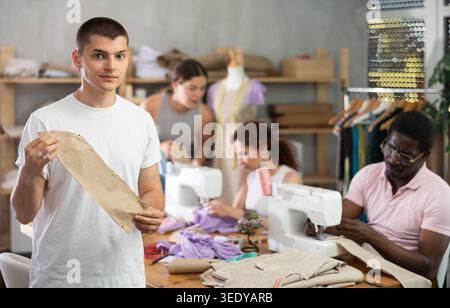 Young guy showing paper pattern in training sewing workshop Stock Photo