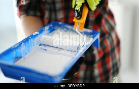 Woman Mixing A Brush In A Tray With A Roller To Get Ready To Paint Walls White Stock Photo