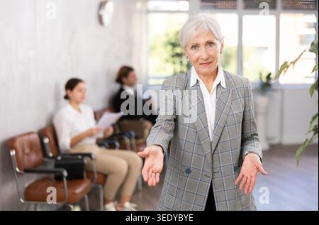 Seniore positive woman extending her hand for handshake in office Stock Photo