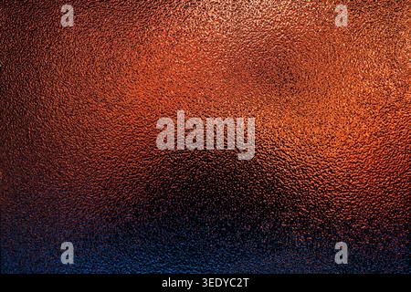 Textured frosted glass background featuring a dramatic gradient from bright copper to dark blue Stock Photo