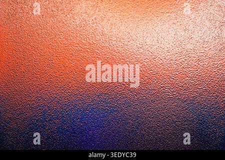 Vibrant textured frosted glass with bright orange to deep blue gradient Stock Photo