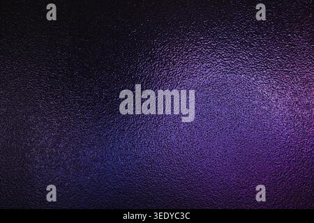 Dark textured glass surface with glowing purple and magenta gradient lighting Stock Photo