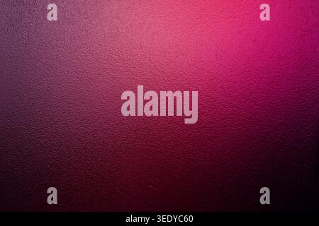 Magenta and pink gradient light on a dark bumpy textured surface Stock Photo