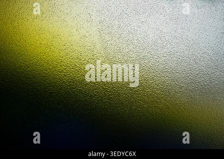 Abstract macro view of bumpy frosted glass illuminated by green and yellow gradient light Stock Photo
