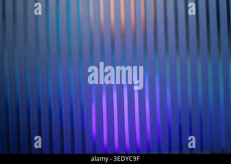 Blurred vertical lines on dark blue glass with purple neon backlight Stock Photo