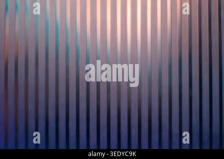 Dark vertical corrugated panel texture with warm orange backlight contrast Stock Photo