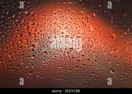 Macro photography of water condensation drops on a glass surface with warm orange illumination Stock Photo