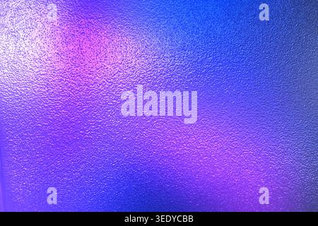 Textured rough surface with a vibrant blend of blue and magenta gradient lighting Stock Photo