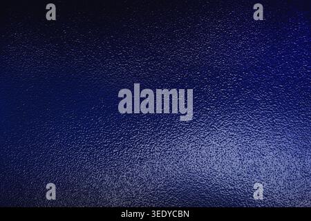 Close up of deep blue frosted glass texture with illuminated grainy surface Stock Photo