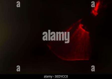 Abstract glowing red light folding in the dark resembling a sweeping fabric motion Stock Photo